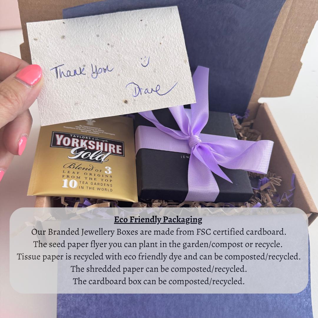 A hand holding a note of thanks next to a gift box with a purple ribbon, and a note about eco-friendly packaging for the jewelry boxes.