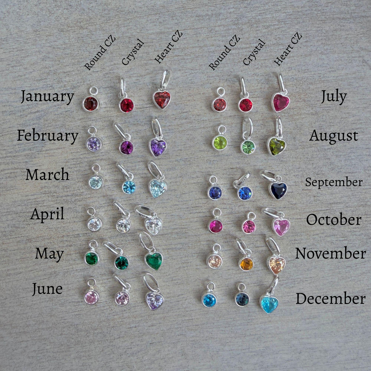 a collection of various charms, each representing a different month of the year, arranged on a wooden surface.