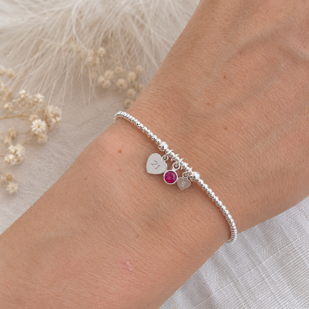 A silver bracelet with charms on a person's wrist.