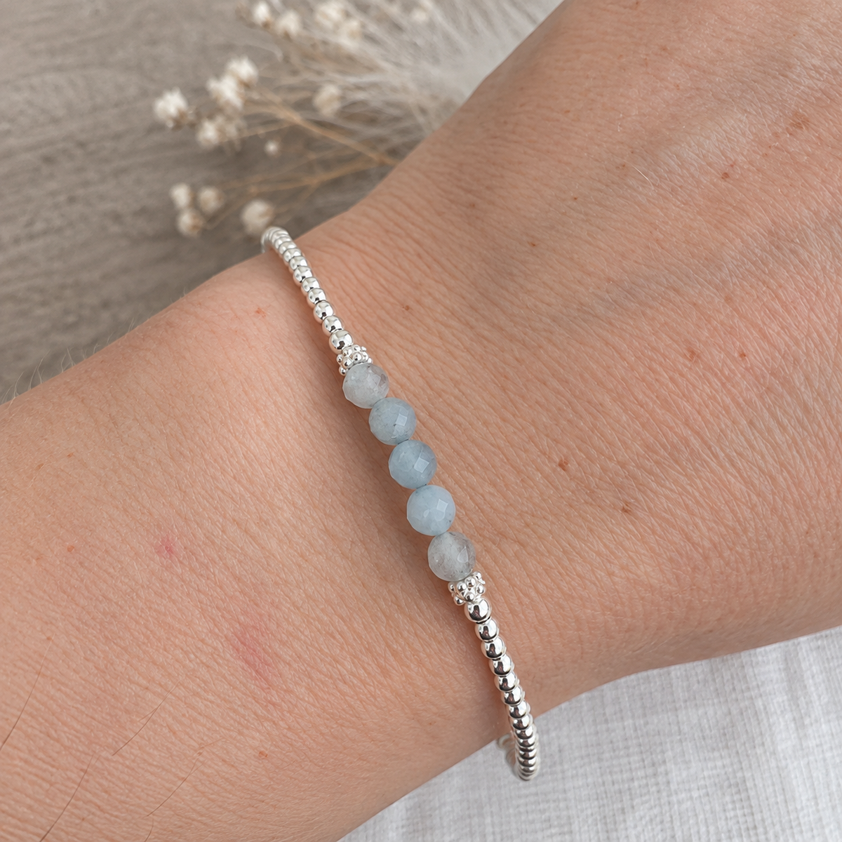 A silver bracelet with blue stones is worn on a person's wrist.