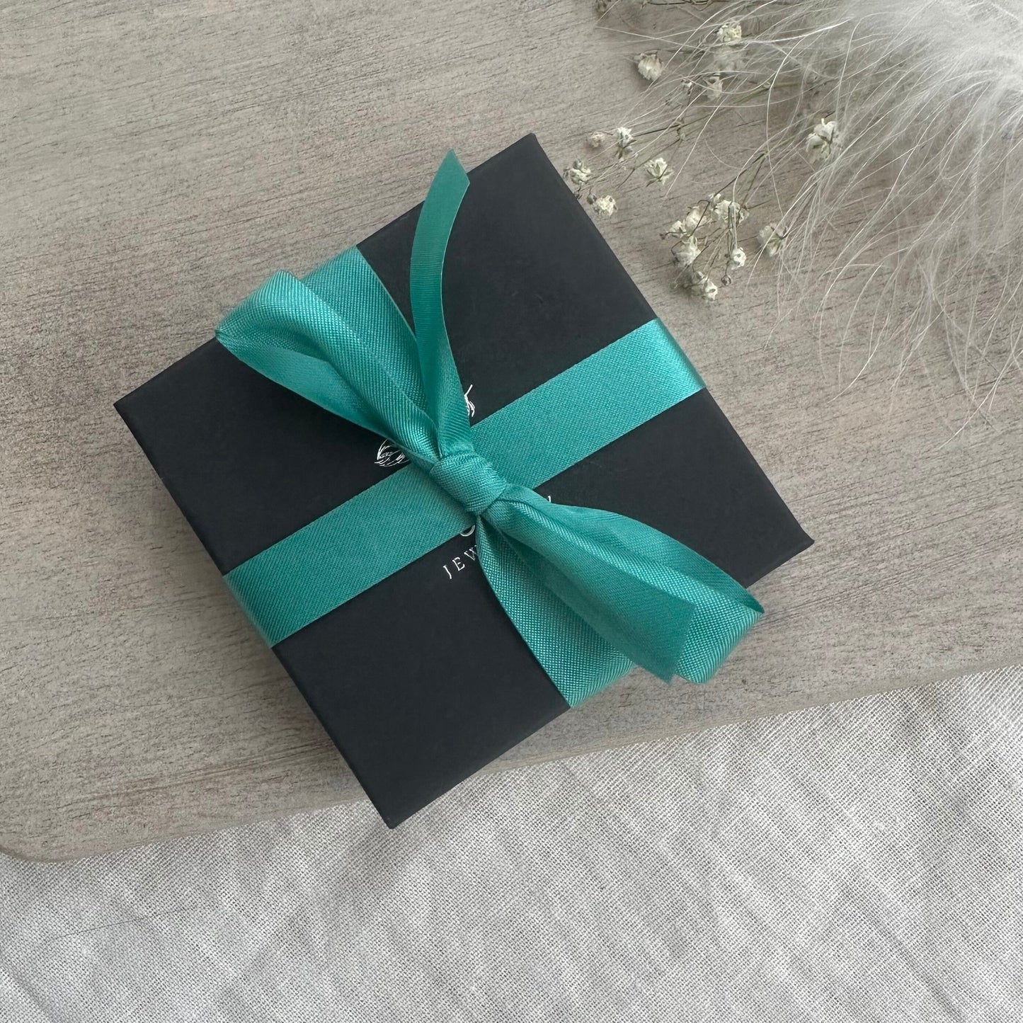 a gift wrapped in a black and teal ribbon